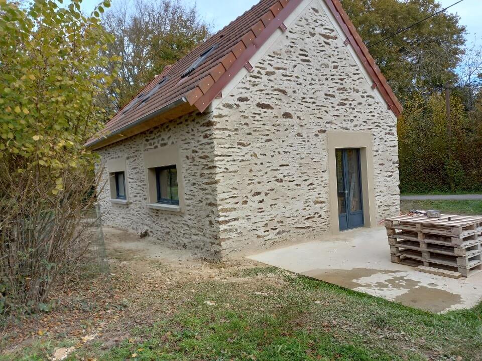 Construction d'une maison typique creusoise avec des pierres locales et de l'enduit à la chaux.